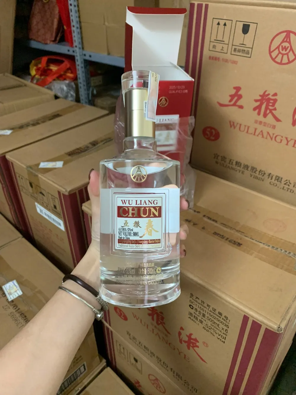 Rượu Wu Liang Chun Ngũ Lương Xuân 500ml Cầm chai rượu Wu Liang Chun Ngũ Lương Xuân nhãn vàng đỏ