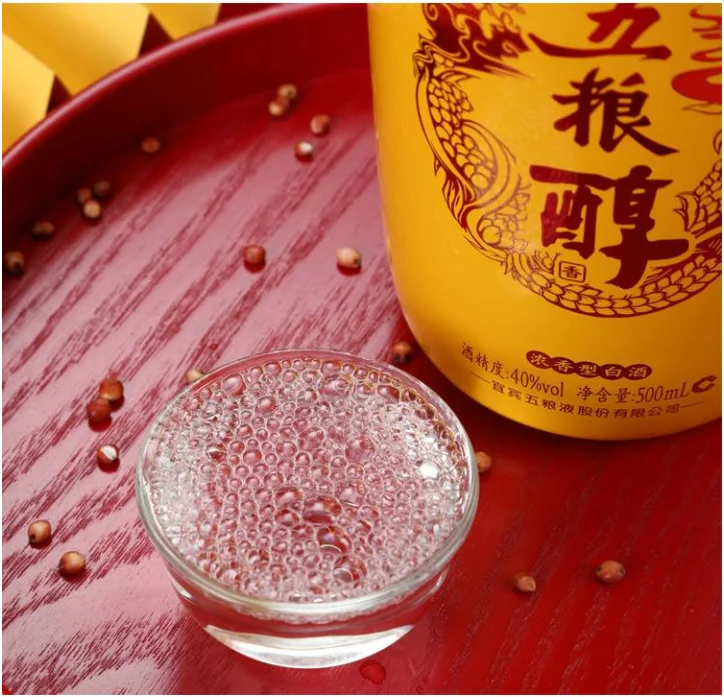 Rượu Wuliang Mellow Ngũ Lương Thuần 40 Độ 500ml Chén rượu Wuliang Mellow Ngũ Lương Thuần 40 độ sóng sánh bên chai rượu trên khay đỏ